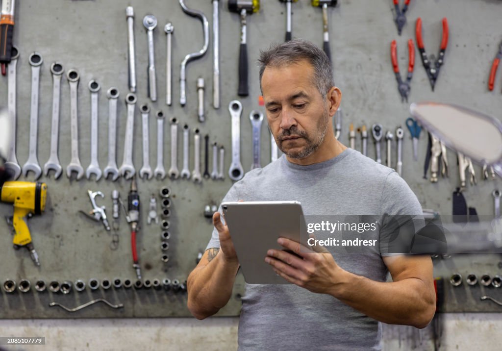 Garage owner working at an Auto Repair Shop using a digital tablet