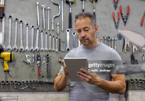 Garage Owner Working At An Auto Repair Shop Using A Digital Tablet High-Res Stock Photo