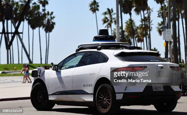Waymo autonomous self-driving Jaguar taxi drives along Venice Beach on March 14, 2024 in Los Angeles, California. Beginning today, Waymo One is...