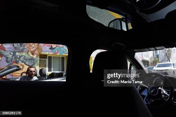 Driver looks at a Waymo autonomous self-driving Jaguar taxi driving along a street near Venice Beach on March 14, 2024 in Los Angeles, California....