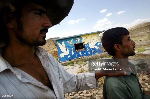 Northern Iraqi Kurds Hendrin Usman and Ubeid Hasen stand before their house adorned with doves June 16, 2003 in a village near Erbil, Iraq. The...