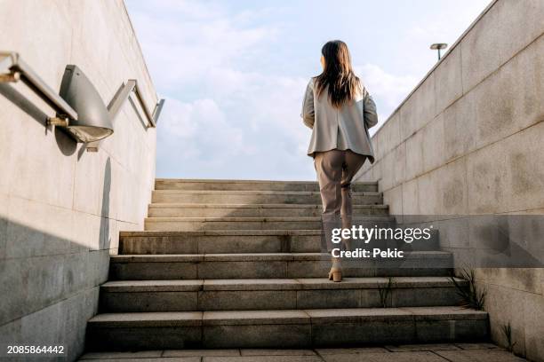 vue arrière d’une femme d’affaires montant les escaliers à l’extérieur - escalier photos et images de collection