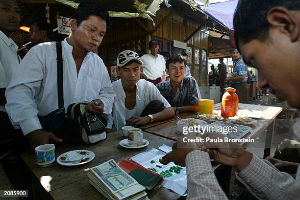 Burmese Jade dealers buy and trade Jade stones as a dealer examines the goods at the Jade market June 15, 2003 in Mandalay, Myanmar. The country...