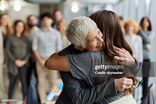 happy senior businesswoman embracing her colleague in the office. - entrepreneur stockfoto's en -beelden
