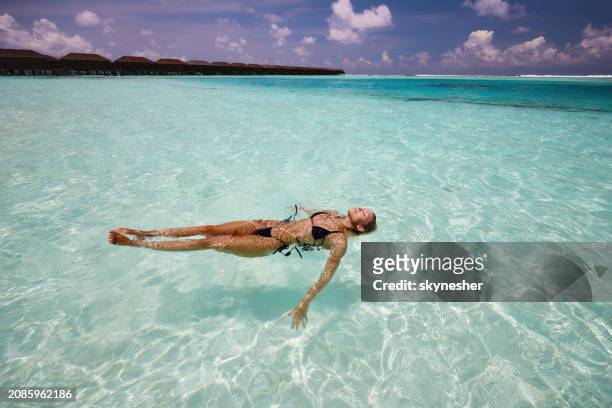 young carefree woman floating in sea. - meeru island stock pictures, royalty-free photos & images