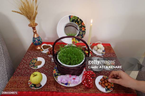 An Iranian decorates a table with "Haft Seen" or "Seven S" in Tehran on March 17 in preparation for Nowruz, the Persian New Year. Iranians celebrate...