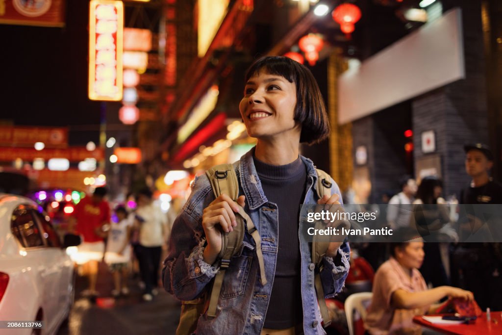 Happy Asian tourist enjoying on the city street at night.