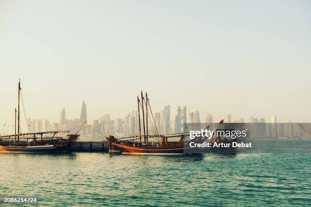 traditional boats in the bay of doha with the modern city skyline in the background. - harbor east stock pictures, royalty-free photos & images