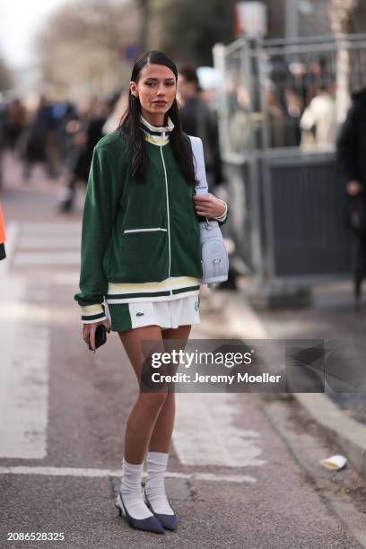 Heloise Agostinelli seen wearing a green and white Lacoste tennis skirt, green Lacoste jacket, white socks, grey heels, Lacoste white leather bag...