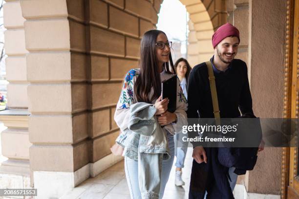 group of cheerful male and female students arriving to college building - male student wearing glasses with friends stock-fotos und bilder