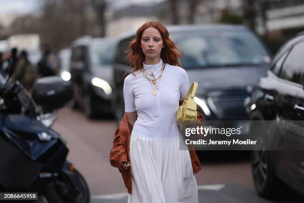Marie Gaguech seen wearing a white Lacoste shirt, skirt, orange Miu Miu leather jacket, yellow Miu Miu handbag, golden necklace chains outside...
