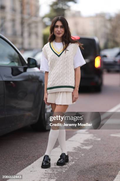 Belen Hostalet seen wearing a full Lacoste look, white shirt, creme sweater vest, skirt, high socks, black loafer outside Lacoste Show during the...