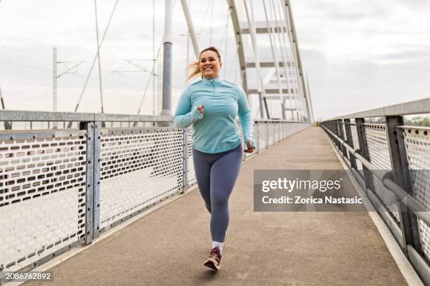 overweight young woman exercising on bridge - obesitas stockfoto's en -beelden