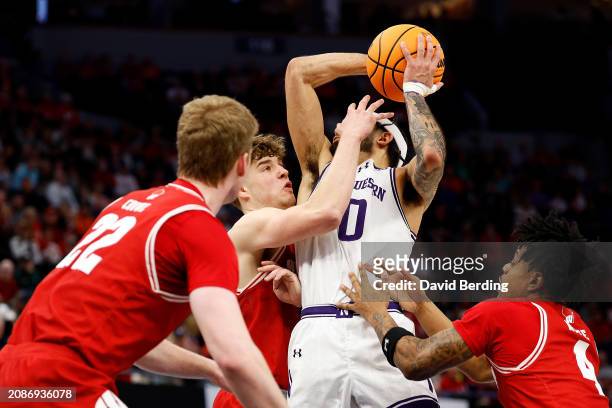 Boo Buie of the Northwestern Wildcats goes to the basket against Max Klesmit of the Wisconsin Badgers in the first half at Target Center in the...