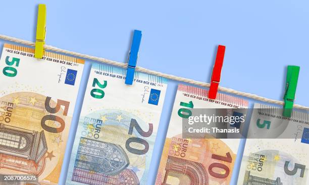 european union banknotes drying on a clothesline - one hundred euro note stock pictures, royalty-free photos & images