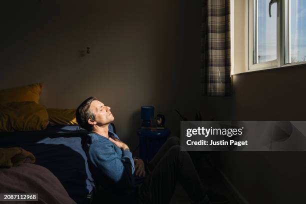 a mature man practices mindfulness in his bedroom - chap stock pictures, royalty-free photos & images