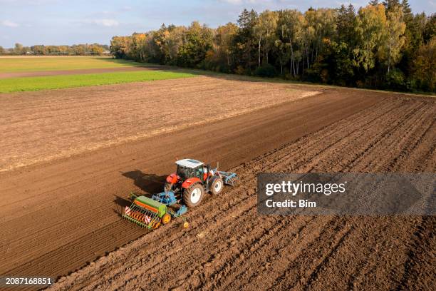 red tractor sowing plowed field - espalhar imagens e fotografias de stock