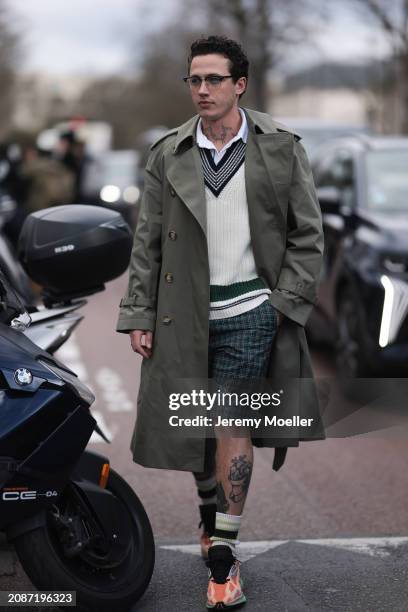 Guest seen wearing a khaki trenchcoat, white Lacoste pullover, white shirt, green checkered pants, socks and orange sneaker outside Lacoste Show...