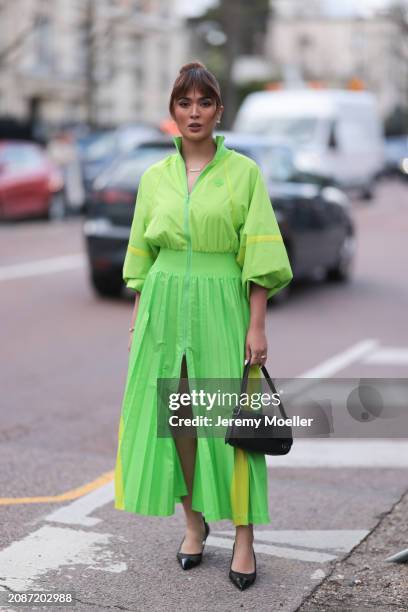 Guest seen wearing a neon green long Lacoste two piece, jacket and skirt, black leather bag and shoes outside Lacoste Show during the Womenswear...