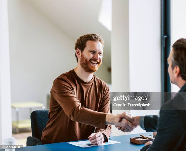 two professionals in a friendly handshake during a business meeting - entrevista imagens e fotografias de stock