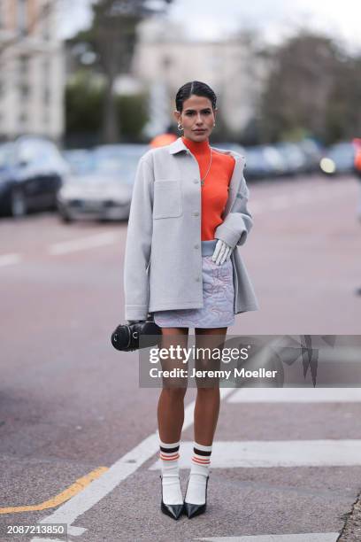 Guest seen wearing orange turtleneck, creme jacket, light rose skirt, white socks, black heels and a Lacoste leather bag outside Lacoste Show during...