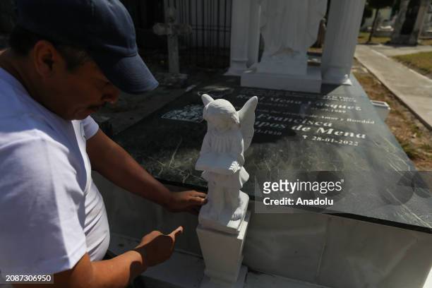 Hugo Menjivar, Salvadoran sculptor and assistant to Roberto Mena, places a piece of sculpture on a family tomb during work at the family business...
