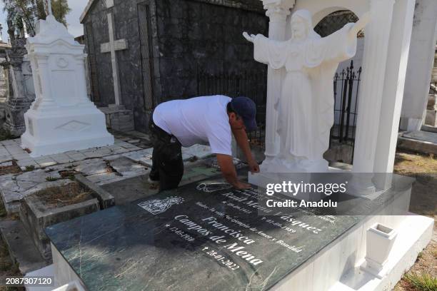Hugo Menjivar, Salvadoran sculptor and assistant to Roberto Mena, cleans a grave with a work of Mena sculpture during work at the family business...
