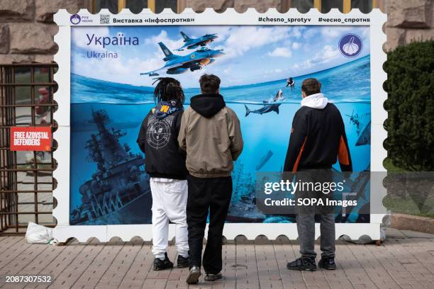 People look at a poster-size stamp depicting a Russian warships sunk after Ukrainian attacks in the Black Sea, in central Kyiv. This stamp is not an...