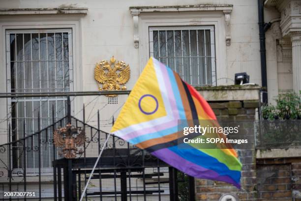 Progress Pride flag flies by the coat of arms of Russia during the protest. Peter Tatchell human rights campaigner organised a protest outside the...