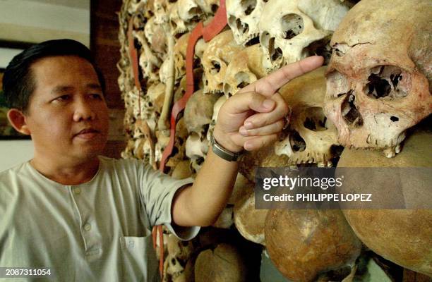 Cambodian genocide museum's director Sopeara Cheay points his finger to a damaged skull on the twenty-year-old Cambodian map made with skulls and...