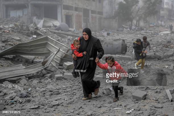 Palestinians flee the area after Israeli bombardment in central Gaza City on March 18 amid the ongoing battles between Israel and the militant group...