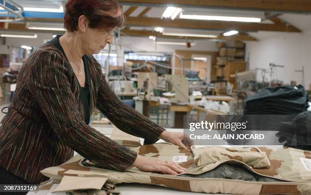 Mrs Françoise Calvo, co-chairwoman of French Barmette textile company adjusts the last batch of flakjackets ordered by the French army in their plant...