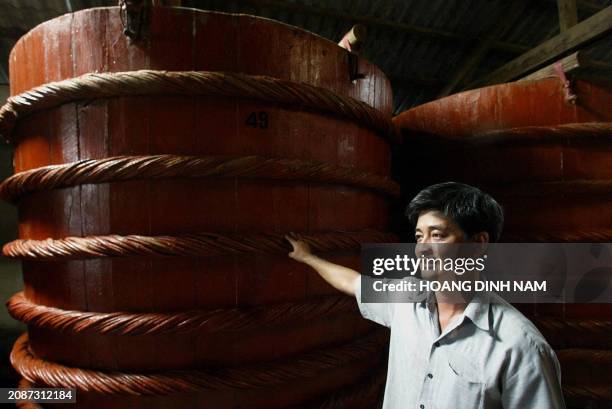 Nguyen Huy Hoang, deputy director of his family-owned Nuoc Mam Thanh Ha Company stands next to a wooden vat of nuoc mam in southern Phu Quoc island,...
