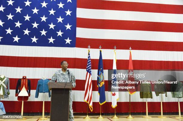 Before a large American flag and a display of historic uniforms, Brigadier General Renwick Payne presides over a traditional ceremony commemorating...
