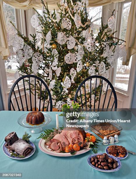 Holiday tablescape including, clockwise from top left, figgy pudding, sweet potato soufflé, sticky buns, roasted chestnuts, glazed ham and Buche de...