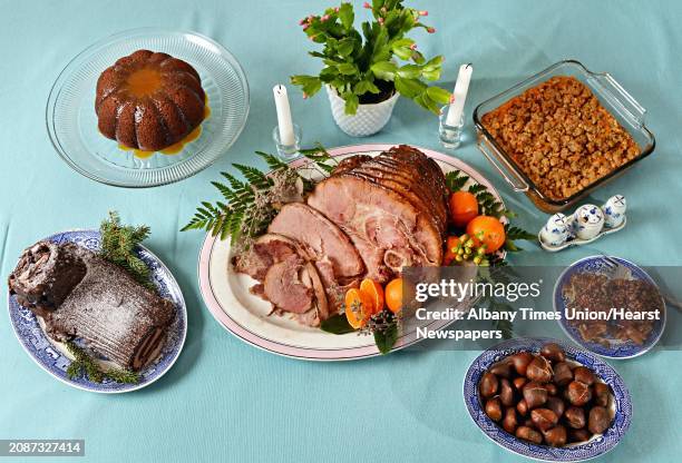 Holiday tablescape including, clockwise from top left, figgy pudding, sweet potato soufflé, sticky buns, roasted chestnuts, glazed ham and Buche de...