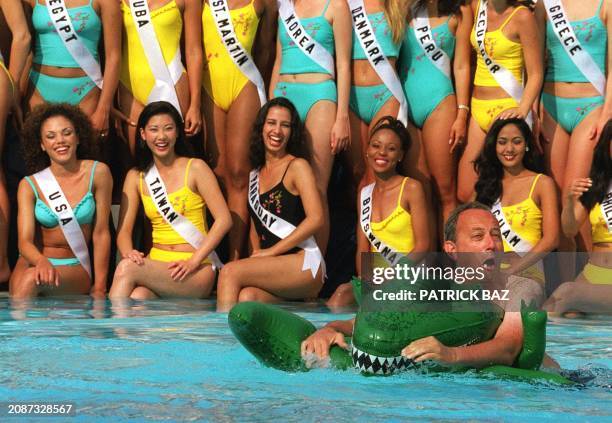 Video director Paul Cockerill swims on an inflatable dragon as Miss Universe 2000 contestants Lynette Cole, Miss USA 2000, Lei-Ann Chang, Miss Taiwan...