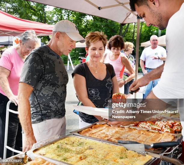 Mike, second from left, and Peggy Conway of Hadley buy European delicacies from Armin Hrelja, right, at the New Covenant Presbyterian Church Farmer's...