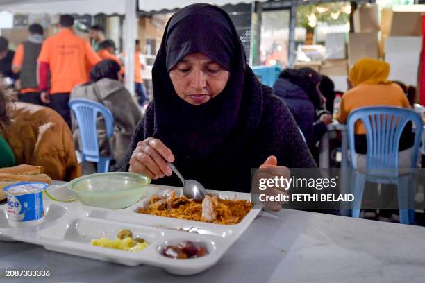 Tunisian man has her fast breaking 'iftar' meal at sunset at a restaurant serving poor families, during the Muslim holy fasting month of Ramadan, in...