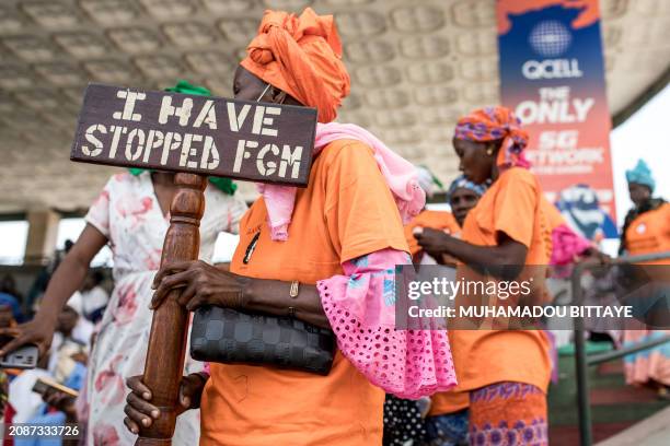 Anti Female Genital Mutilation protester holds a placard outside the National Assembly in Banjul on march 18 during the debate between lawmakers on a...