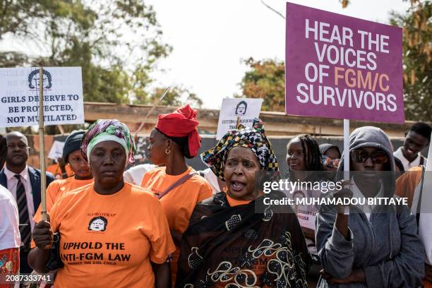 Anti Female Genital Mutilation protesters hold placards outside the National Assembly in Banjul on march 18 during the debate between lawmakers on a...