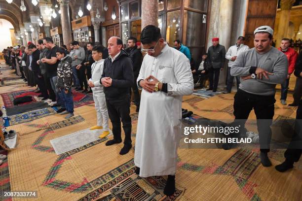 Muslim devotees perform an evening prayer known as 'Tarawih' in Tunisian capital's historic Zituna mosque in the heart of Tunis' old quarter during...