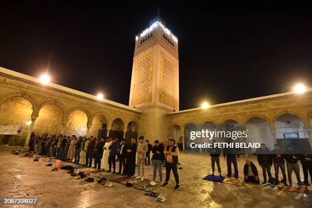 Muslim devotees perform an evening prayer known as 'Tarawih' in the courtyard of the Tunisian capital's historic Zituna mosque in the heart of Tunis'...