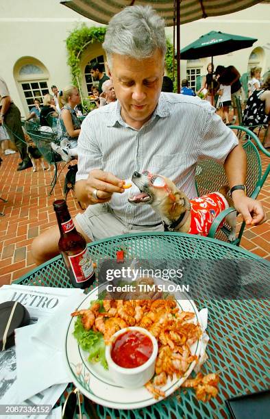 Andy Messing of Alexandia feeds his Jack Russel Terrier "Dick the Dog" a spicey shrimp at the Doggie Happy Hour held on Tuesdays and Thursdays at the...