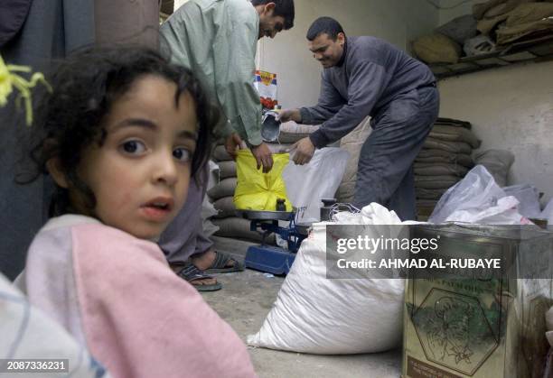 An Iraqi girl sits in a food distribution center in Baghdad 03 April 2003. US troops reached baghdad airport today after fierce fighting with Iraqi...