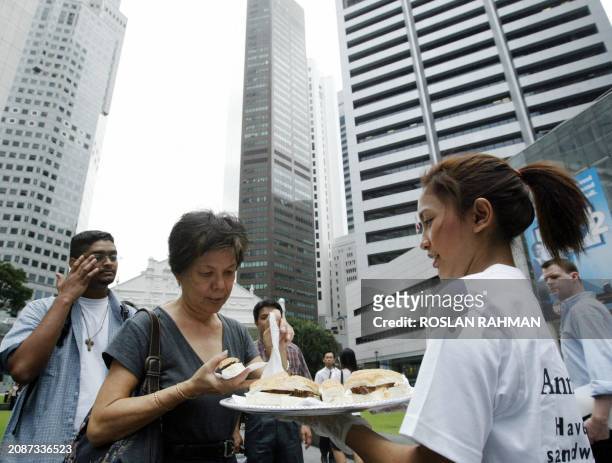 Restaurant staff give out free steak sandwich to passers-by at the financial district of Singapore 29 August 2003. Singapore's goods and services tax...