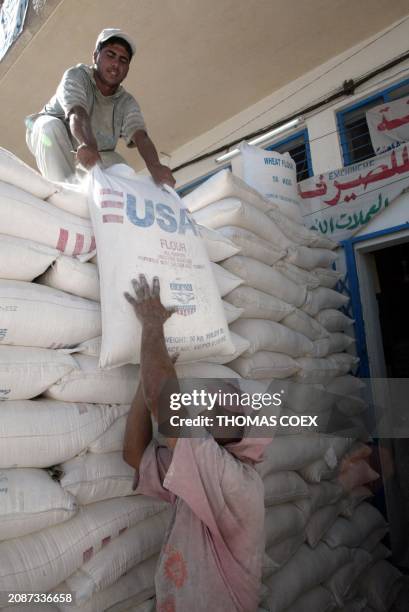 Iraqi workers haul sacks of flour donated by the United States at an open black market in the Sadr City locality of Baghdad 11 September 2003. The...