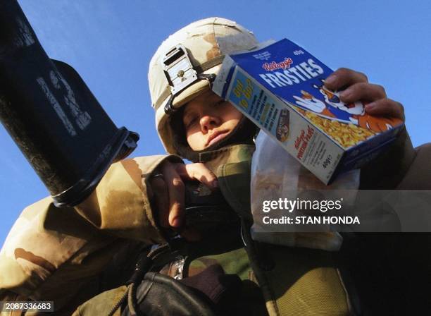 Army Spcl. Michelle Long of the 401 MP Company, 720 MP Battalion, adjusts her equipment while holding her breakfast cereal, 14 February 2004, during...