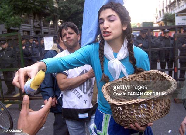 Demonstrator gives out bananas wrapped with a flag in Buenos Aires, Argentina 25 May 2002. Una manifestante contraria al gobierno, ataviada como un...