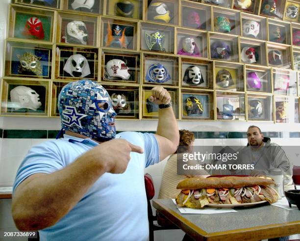 Mexican wrestler "Superastro" poses 21 August with his invention the "Gladiator" hoagie at his "El Cuadrilátero" restaurant in Mexico City. The...